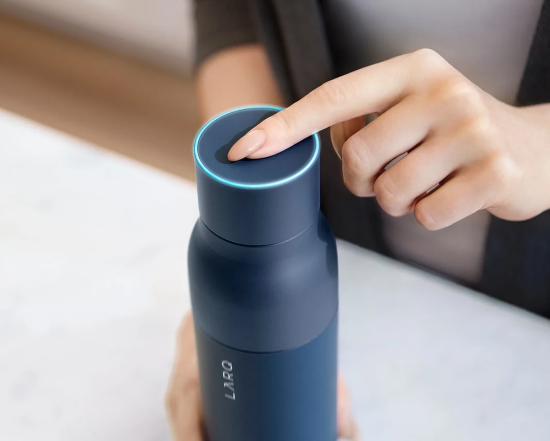 A woman's hands activating the lid of a high-tech waterbottle. Shows finger depressing cap to light up rim.