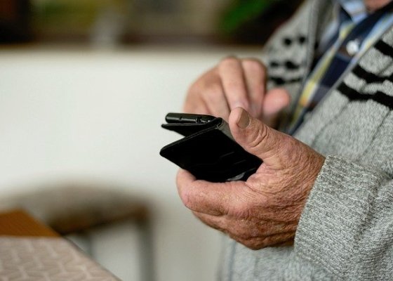 The hands of a senior holding a mobile device.