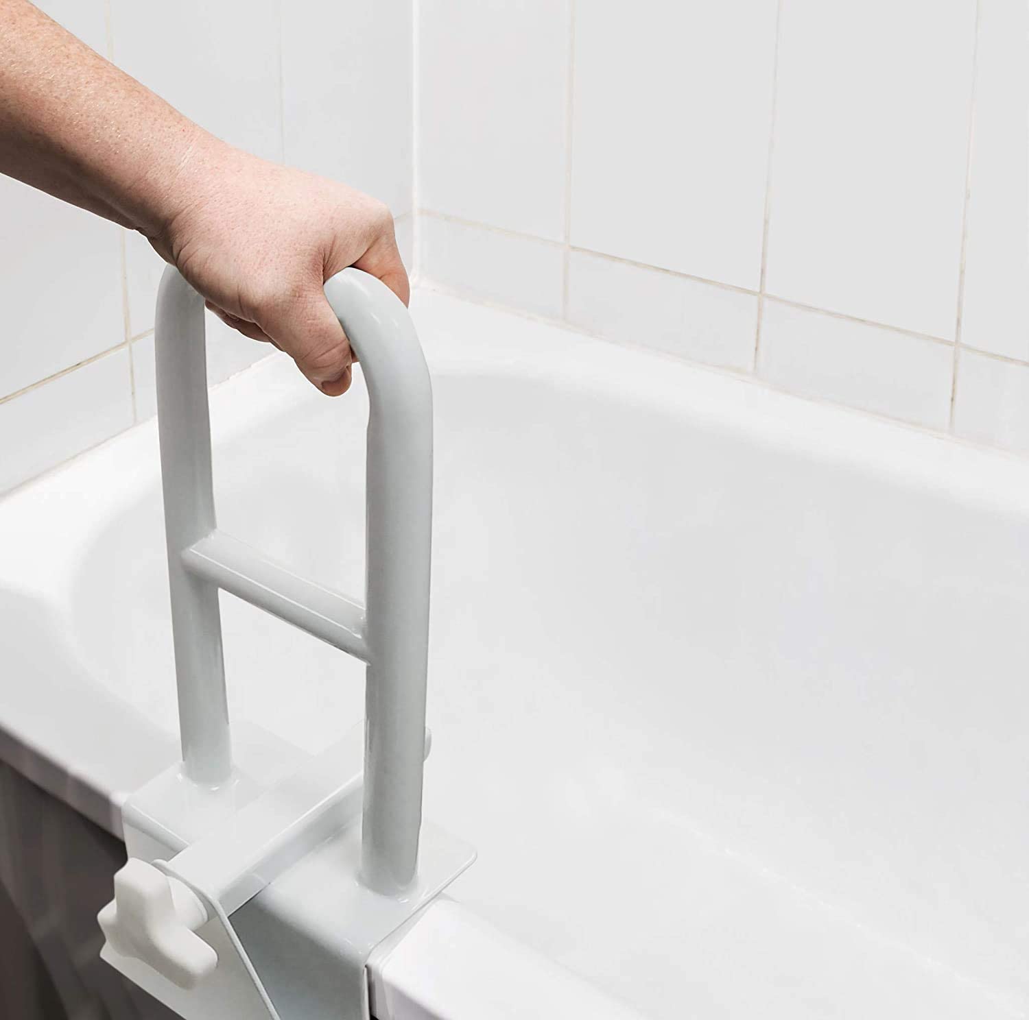 A hand grasps a grab-bar that is clamped to the side of a tub.