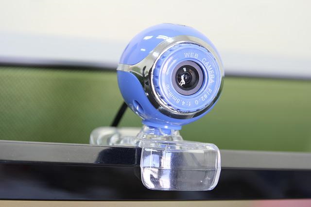 Closeup of a web cam resting on edge of a monitor.